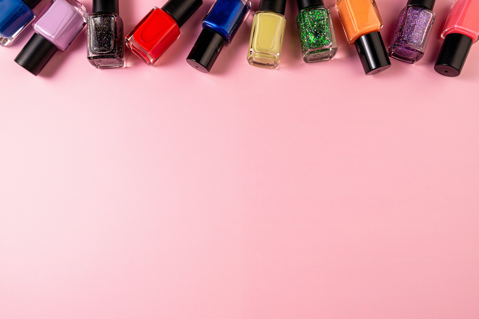 Set of various nail polish bottle on pink background with copy space. Stylish trendy nail polish